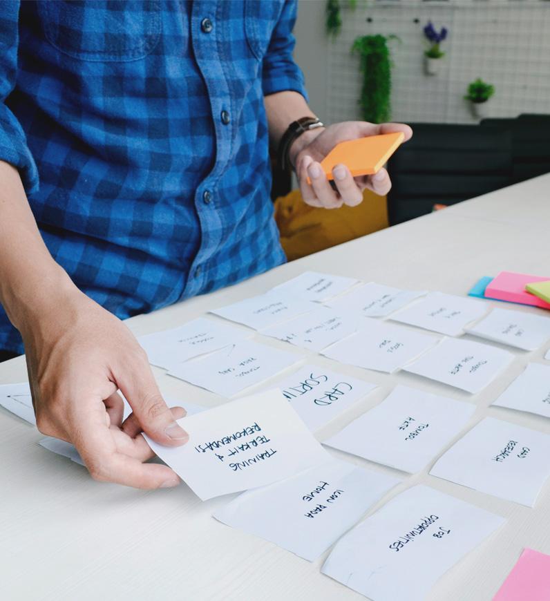 A person holding a paper with sticky notes, conducting UX research to understand business and user needs for data-driven decisions.